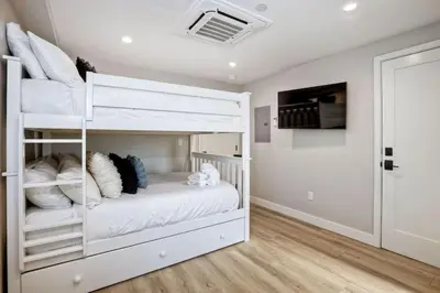 a bedroom with white bunk beds and a tv at NEW Luxury Beach Home I 3BR I Balcony I Firepit in San Diego