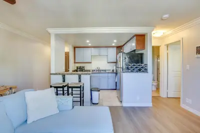 a living room with a blue couch and a kitchen at Sunny Imperial Beach Condo - Walk to Ocean! in Imperial Beach
