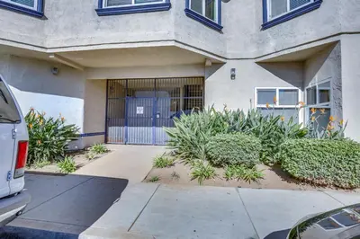 a building with a gate and plants in front of it at Sunny Imperial Beach Condo - Walk to Ocean! in Imperial Beach