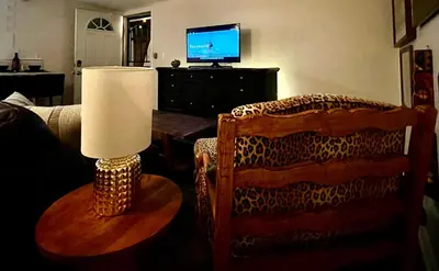 a living room with a chair and a table and a television at Mile to Beach! Tiki Master Suite in Oceanside