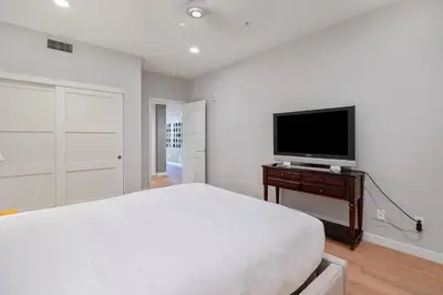 a white bedroom with a bed and a flat screen tv at Escape to Neptune in San Diego