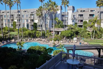 a view of a swimming pool with palm trees and buildings at Oceanfront condo at North Coast Village in Oceanside