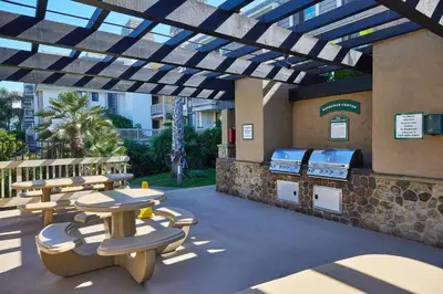 a patio with a grill and tables and benches at Oceanfront condo at North Coast Village in Oceanside