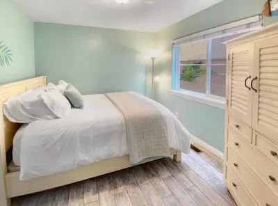 a bedroom with a bed with white sheets and a window at Massive Mission Beach Home - Fire Pit & Deck in San Diego