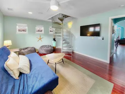 a living room with a blue couch and a staircase at Massive Mission Beach Home - Fire Pit & Deck in San Diego