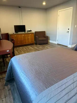 a bedroom with a bed and a chair and a television at Valley Motel El Cajon San Diego in El Cajon
