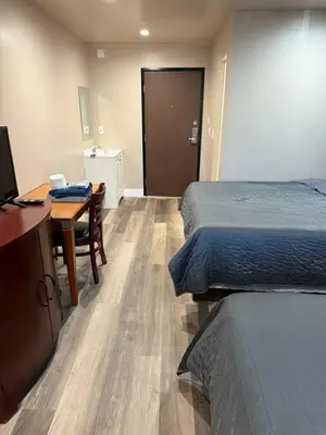a room with two beds and a desk and a table at Valley Motel El Cajon San Diego in El Cajon