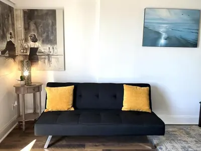 a black couch in a living room with yellow pillows at Ocean Bluff Hideaway Unit B in San Clemente