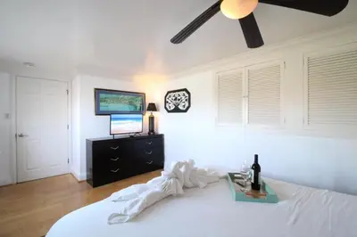a bedroom with a white bed with a ceiling fan at Ocean Bluff Hideaway Unit B in San Clemente