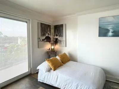 a white bedroom with a bed and a large window at Ocean Bluff Hideaway Unit B in San Clemente