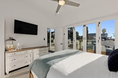 a white bedroom with a bed and a flat screen tv at CB-3900A - Coastal Carlsbad Surfer's Dream in Carlsbad