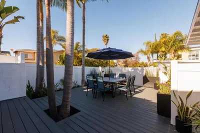 a patio with a table and chairs and palm trees at CB-3900A - Coastal Carlsbad Surfer's Dream in Carlsbad