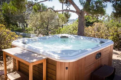 a jacuzzi tub with a bench in front of a tree at Private Hacienda with Heated Pool and Spa with Amazing Views in Del Mar