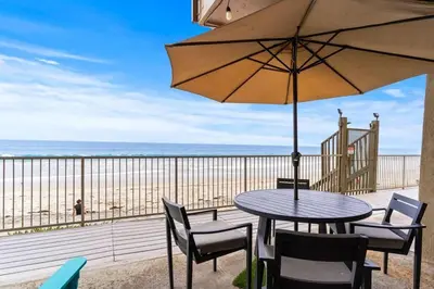 a table with chairs and an umbrella on the beach at A Wave From It All in Carlsbad