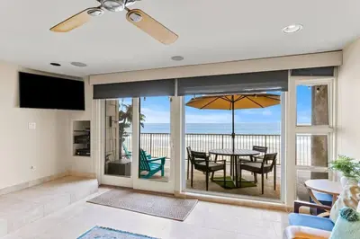 a living room with a table with chairs and an umbrella at A Wave From It All in Carlsbad