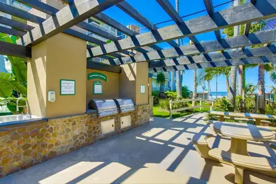 a patio with a grill and tables and chairs at Brooks Beach Vacations Bungalow B116 Oceanside in Oceanside