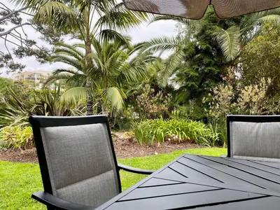 an outdoor table and chairs with palm trees in the background at Brooks Beach Vacations Cottage G5 Oceanside in Oceanside
