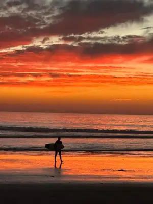 a man walking on the beach with a surfboard at Brooks Beach Vacations House B222 Oceanside in Oceanside