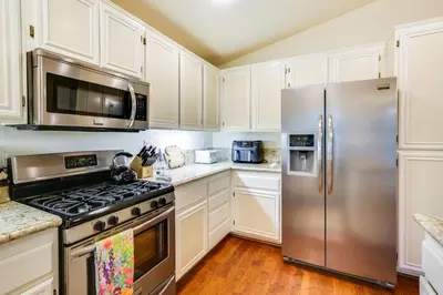 a kitchen with white cabinets and a stainless steel refrigerator at Peaceful El Cajon Vacation Rental with Patio and Yard! in El Cajon