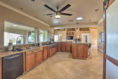 a large kitchen with wooden cabinets and a ceiling fan at Charming Temecula Home with Hot Tub, Mountain Views! in Temecula