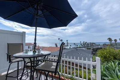 a table and chairs on a balcony with an umbrella at Spacious Ocean View Blufftop Compound in San Clemente