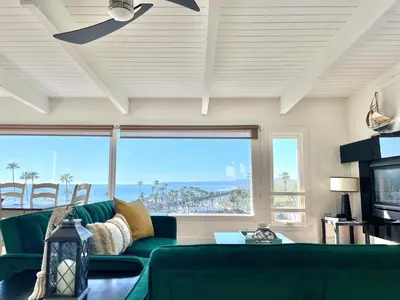 a living room with a green couch and a large window at Panoramic Ocean View Cottage and Hideaway Unit #4 and B in San Clemente