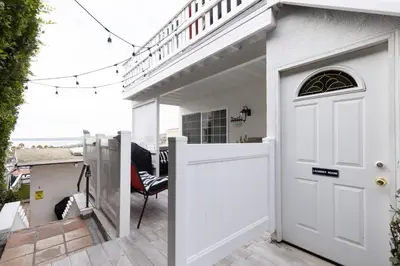 a white door on a white house with a balcony at Sea View Escape Unit #2 in San Clemente