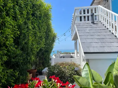a garden with red flowers and a white house at Sea View Escape Unit #2 in San Clemente