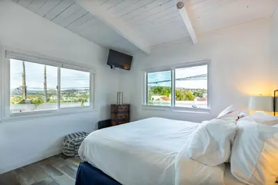 a white bedroom with two windows and a bed at Bright Ocean View Escape Unit #1 in San Clemente