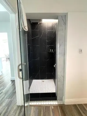 a walk in shower with a black tiled bathroom at Bright Ocean View Escape Unit #1 in San Clemente