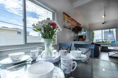 a dining room with a glass table with a vase of flowers at Bright Ocean View Escape Unit #1 in San Clemente