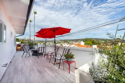 a patio with chairs and red umbrellas on a balcony at Bright Ocean View Escape Unit #1 in San Clemente