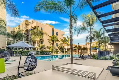 a swimming pool with palm trees and a building at San Diego Stay, Pool, Gym, Near Zoo, Petco Park & SeaWorld in San Diego