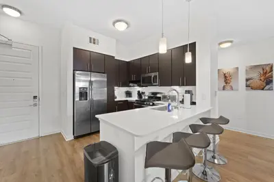 a kitchen with a large white counter and stools at San Diego Stay, Pool, Gym, Near Zoo, Petco Park & SeaWorld in San Diego