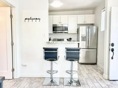 a kitchen with a refrigerator and two bar stools at Charming Flat Near the City in San Diego
