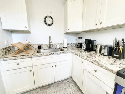 a kitchen with white cabinets and a sink at Charming Flat Near the City in San Diego