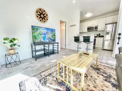 a living room with a table and a kitchen at Charming Flat Near the City in San Diego