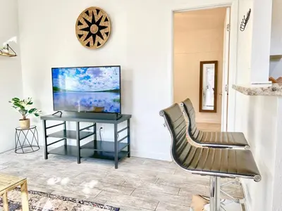 a living room with a tv and a table with a chair at Charming Flat Near the City in San Diego