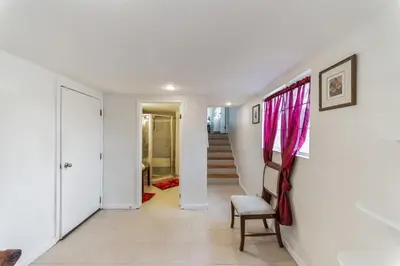 a hallway with white walls and a chair and stairs at Paradise On Earth residence in Lake Elsinore