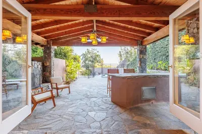 an outdoor patio with a stone floor and a large fireplace at CBS-501 - Cardiff Hillside Hideaway in Cardiff-by-the-Sea