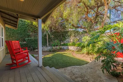 a red chair on a porch with a garden at CBS-501 - Cardiff Hillside Hideaway in Cardiff-by-the-Sea