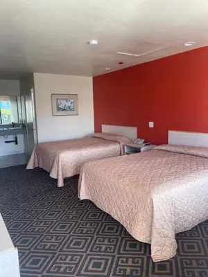 two beds in a hotel room with red walls at Star Lodge Motel-Vista Oceanside in Vista