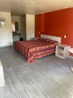 a bedroom with a large bed with a red wall at Star Lodge Motel-Vista Oceanside in Vista