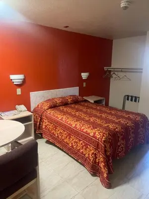a bedroom with a bed with an orange wall at Star Lodge Motel-Vista Oceanside in Vista