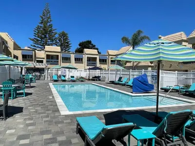 a swimming pool with chairs and an umbrella at Amazing Location - Large and Luxurious 1 Bedroom Beach Condo By Beaches and Attractions in Solana Beach