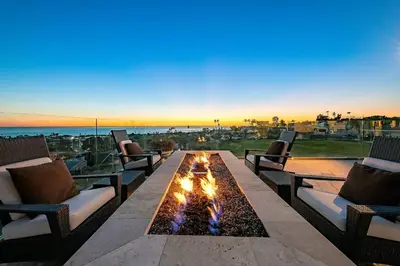 a fire pit on a patio with chairs and the ocean at Ocean View Serenity with Theater and Heated Pool in San Diego