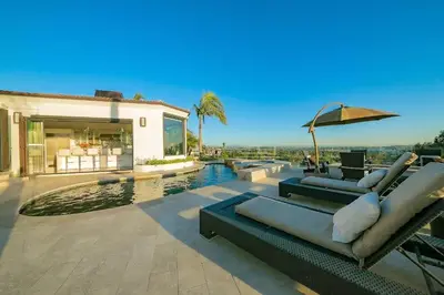 a house with a pool and some chairs and an umbrella at Ocean View Serenity with Theater and Heated Pool in San Diego