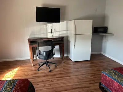 a desk with a computer and a refrigerator in a room at CoachLight Motel in Hemet