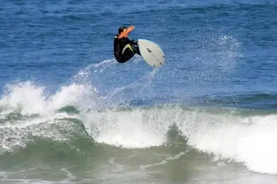 a man riding a wave on a surfboard in the ocean at Sand Pebbles Resort - 1 Bedroom Condo in Great Location Right by the Beaches and Attractions in Solana Beach