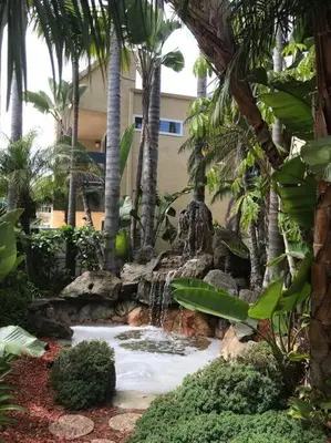 a waterfall in a garden with palm trees at Sand Pebbles Resort - 1 Bedroom Condo in Great Location Right by the Beaches and Attractions in Solana Beach